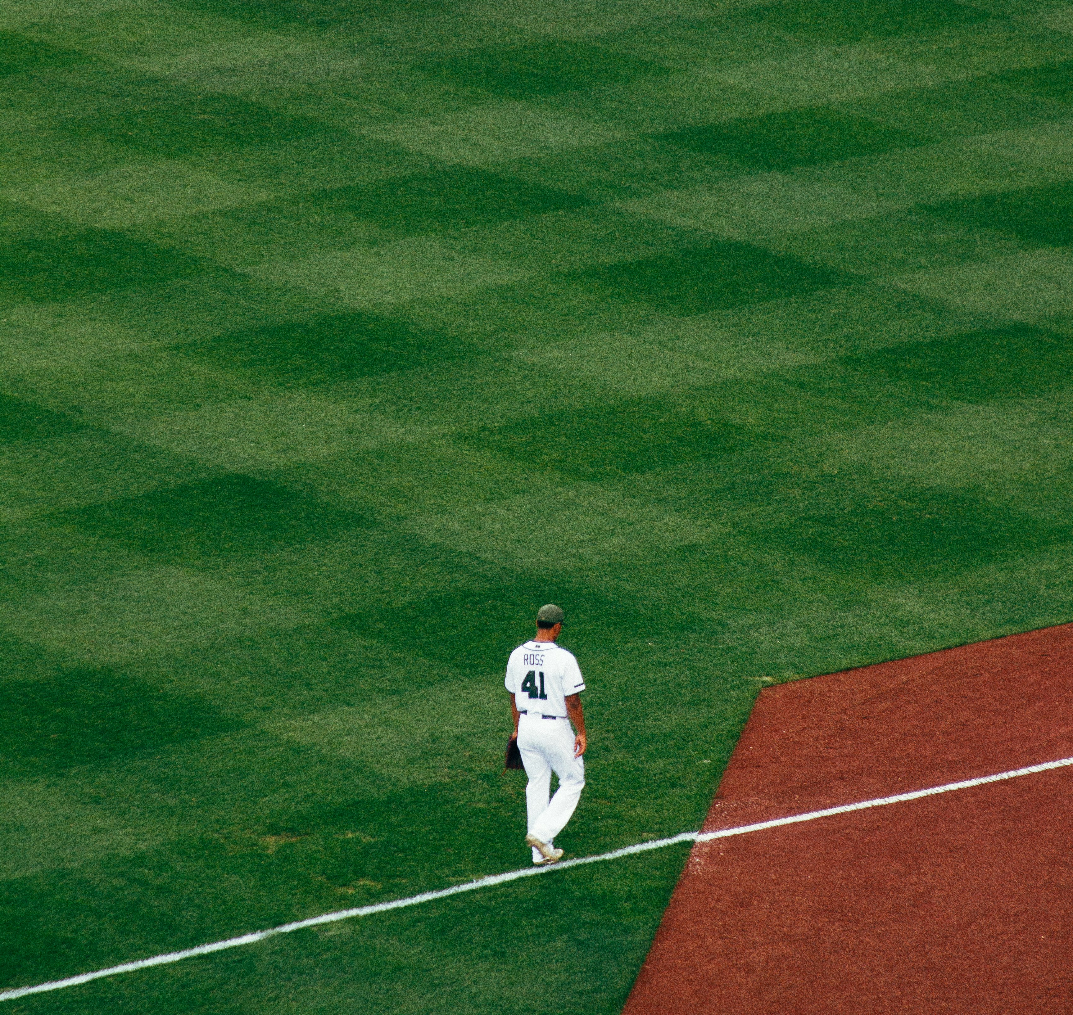 baseball player standing on field steps on white line at daytime
